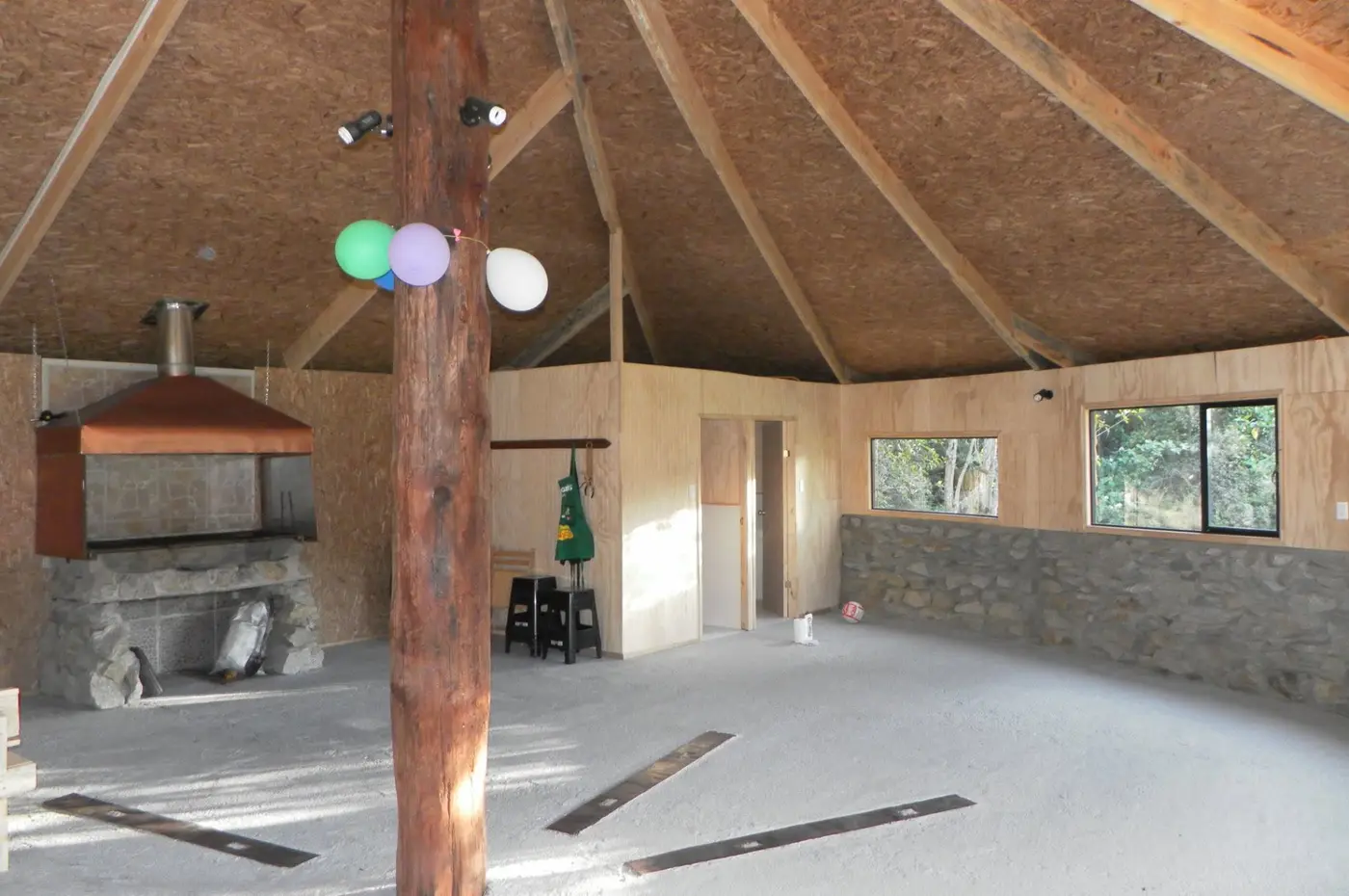 Interior del quincho con estructura de madera y zona de fuego